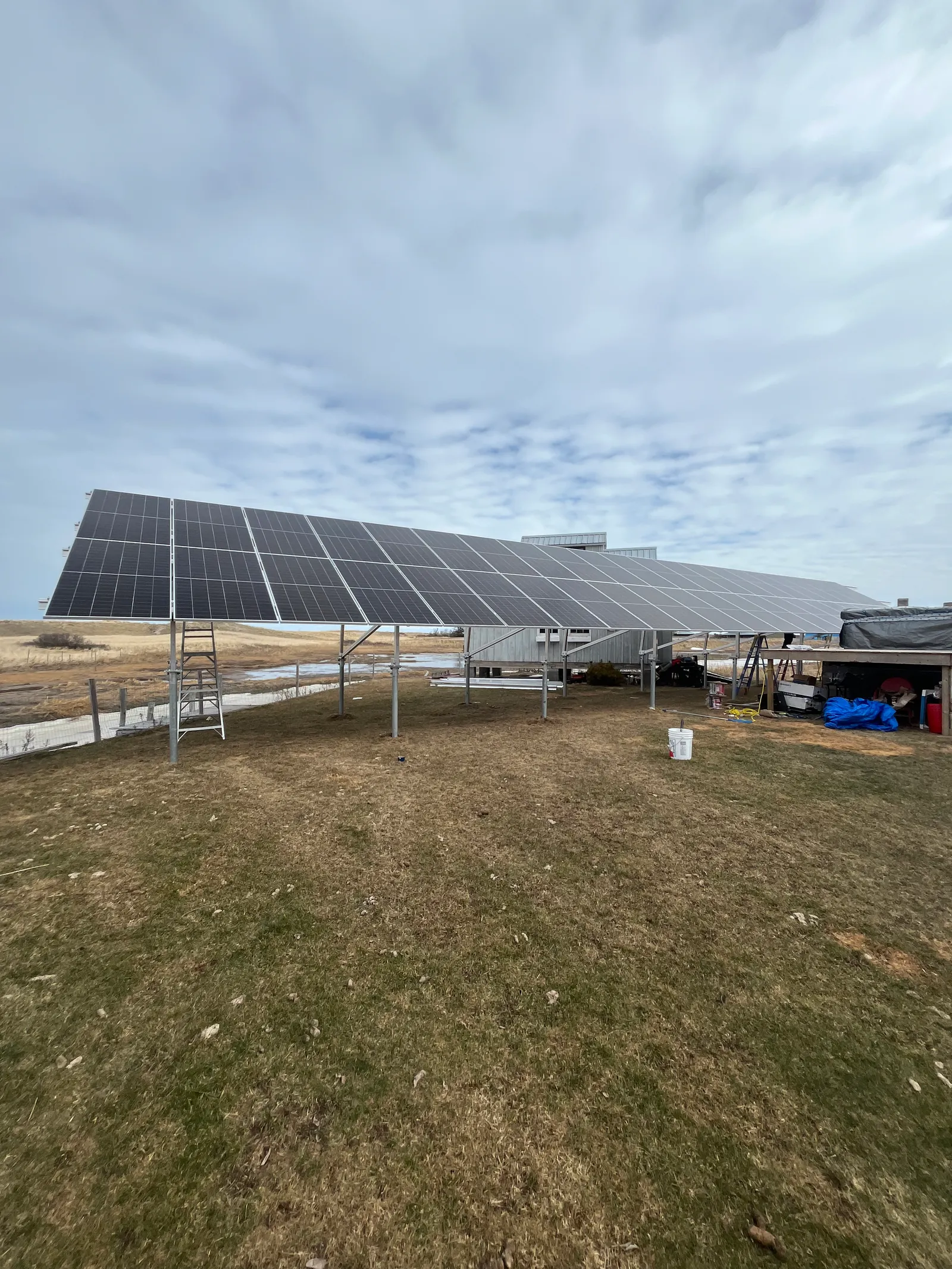 A ground-mounted solar panel array installed beside a building